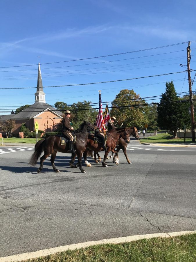 Policemen on horses lead the Parade, holding the colors of Maryland and the U.S.