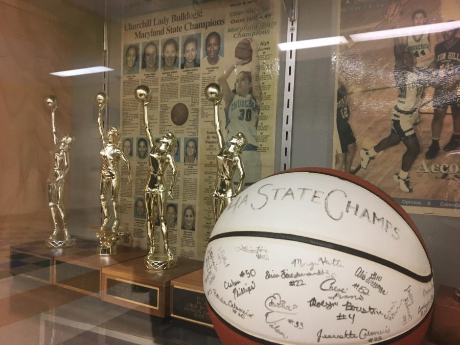 The state championship trophies of the WCHS girls varsity basketball team displayed proudly in front of a news article snippet from 2002 announcing the teams success. 
