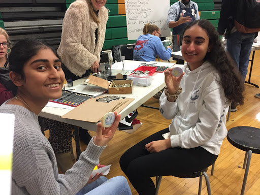 Sophomores Arya Iyer (left) and Sonia Bhatia talking to a staff member from the Stone Branch School of Art. She helped them make buttons - the pair made narwhal buttons, that they colored in on a piece of paper, that was then pressed against the button. 