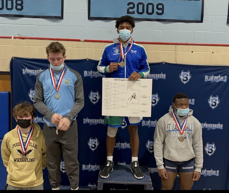 Wrestling team captain, Jaden Selby, stands at the top of the podium after winning Most Outstanding Wrestler at the Grapple at the Brook tournament.