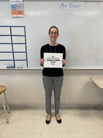 Mrs. Knarr is shown holding her Teacher of the Month certificate. She loves teaching AP Lang and English 10, and has been at WCHS for 21 years.