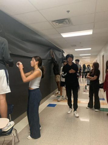 The class of 2024 executive board works on the homecoming mural of pac-man in the math hallway.