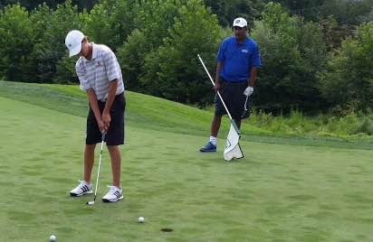 Head Coach Aaron Vactor helps senior Ryan Schechter with his putting.