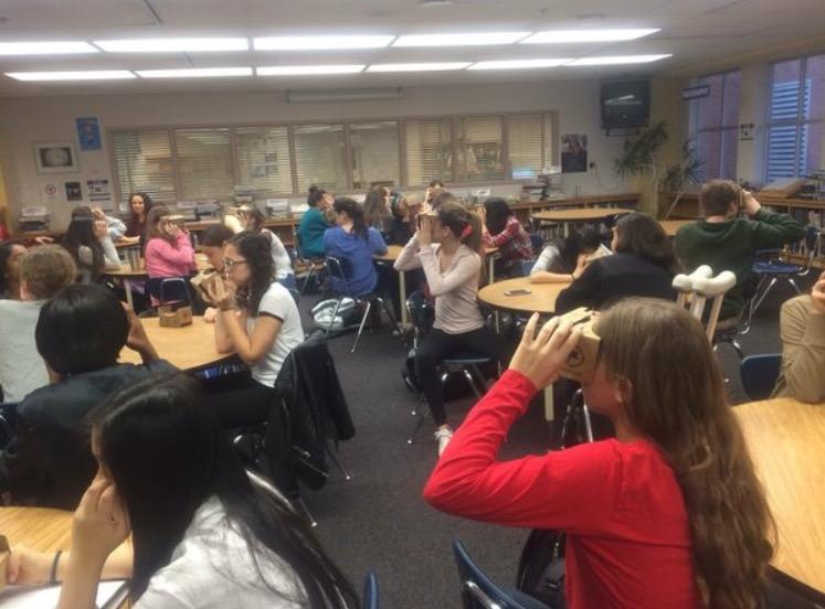 Students in the media center use Google Cardboard to travel to  virtual destinations.