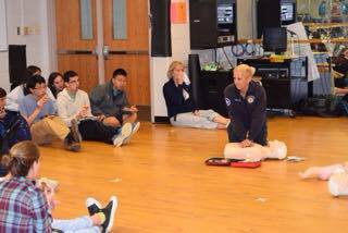 Sergeant Custead instructs a group of juniors how to properly do CPR.