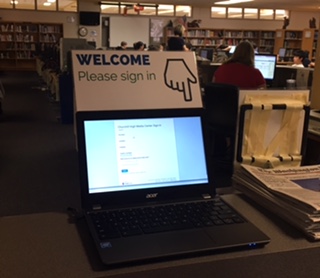 Students use a chromebook to sign into the media center