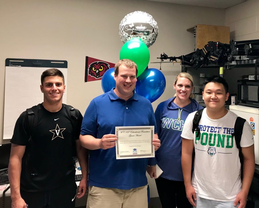 Senior Michael Janis, Technology director Benjamin Schnapp, Ms. Brandice Heckert, and junior William Ahn smiling for the camera just after Schnapp received the grant.