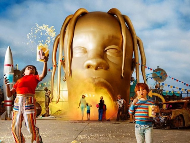 The album cover shows a giant gold statue of Travis Scott’s head as the entrance to an amusement park with children and parents in front of the entrance.