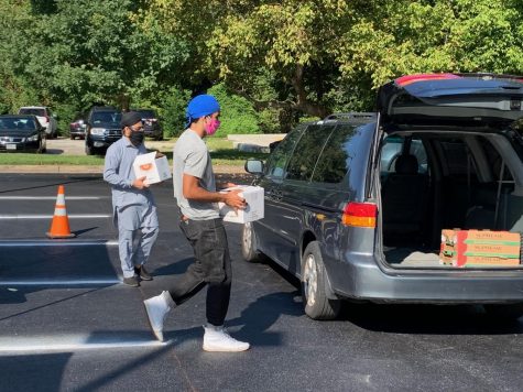 WCHS SGA president Jay Wood (front) and another GGSF volunteer help load cars with fresh produce, hot meals, and other food supplies for those dealing with food insecurity and other food needs. 