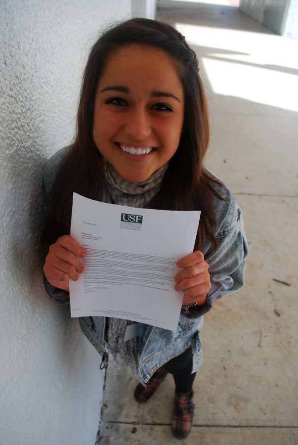 A senior stands smiling as she holds up her acceptance letter to University of Southern Florida. Although some feel overjoyed when they receive letters, these sentiments are not shared with all seniors. 