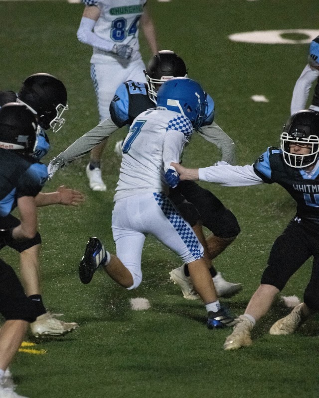 WCHS Senior Jeffrey Yee weaves between two Whitman defenders after catching a pass during the first game of the Bulldogs season.