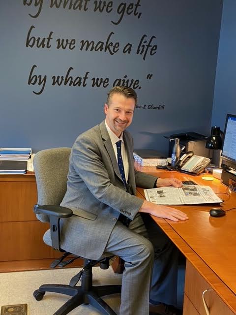 Taylor seated in his office with a copy of The Churchill Observer from when he worked as an administrator at WCHS.