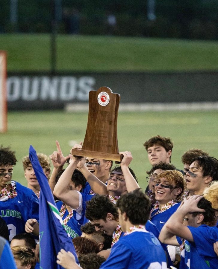 Eliot Dubick lifts up the plaque as the whole team runs to cheer around him. 