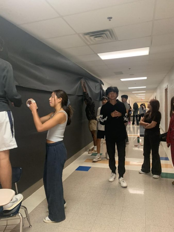 The class of 2024 executive board works on the homecoming mural of Pac-Man in the math hallway.