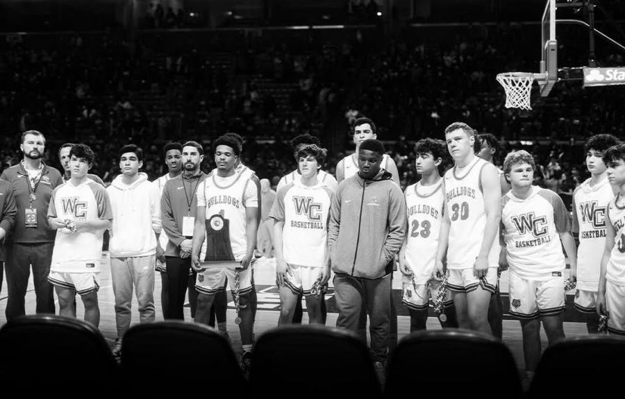 After losing the 2022 State Championship, the WCHS basketball team poses with the runner-up trophy with grim looks on their faces.