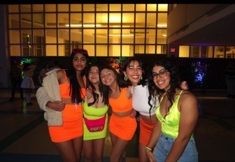 Rubani Singh and fellow WCHS seniors pose in the cafeteria during the GLOW dance. Their neon outfits popped against the dark setting.
