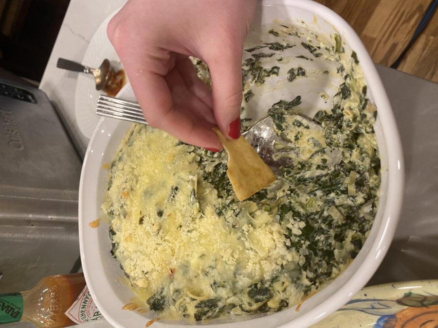 A pita chip gets dipped into spinach and artichoke dip that was offered as one of many food options at a Super Bowl party on Feb. 12.