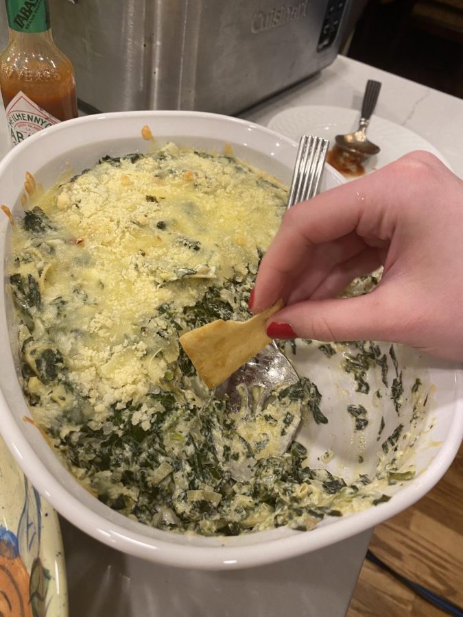 A pita chip gets dipped into spinach and artichoke dip that was offered as one of many food options at a Super Bowl party on Feb. 12.
