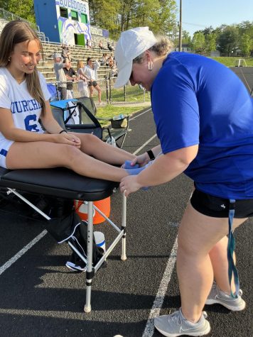 Kisney Gunn (right) wraps student Summer Polhemus ankle before her varsity lacrosse game on April 20, 2023. This is one of the many responsibilities of Gunn during a sporting event at WCHS.
