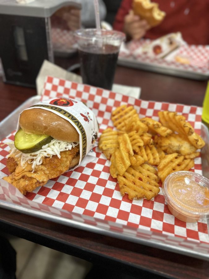 Inside the Rockville Pike location of Hangry Joe’s Restaurant, their spicy chicken sandwich is photographed with a side of seasoned waffle fries, Diet Coke and the signature “hangry sauce.”