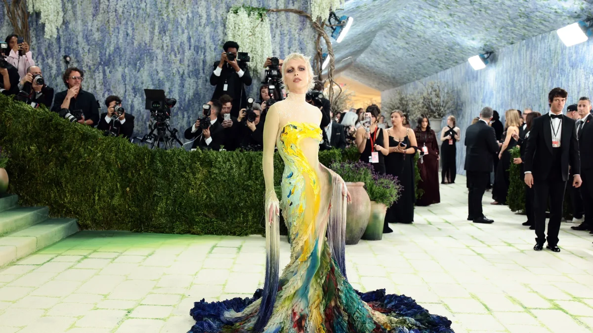 Emma Chamberlain poses for the papparizi in her custom design gown based off Van Goghs Starry Nights. The hues of blue, yelllow, and and green all come together to resemble the famous painting.